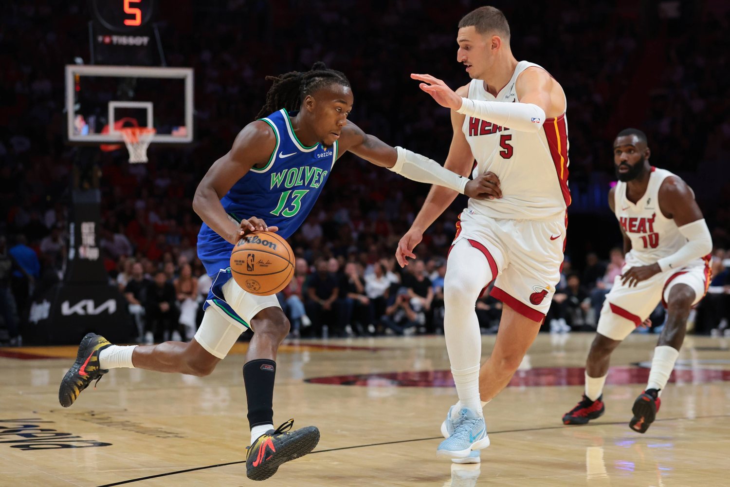 Ayo Dosunmu drives past Nikola Jovic in a blue Wolves uniform in Miami.