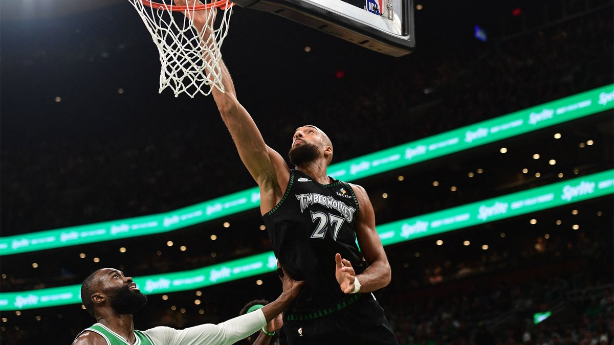 Rudy Gobert lays the ball in at the rim while Jaylen Brown of the Celtics looks on.