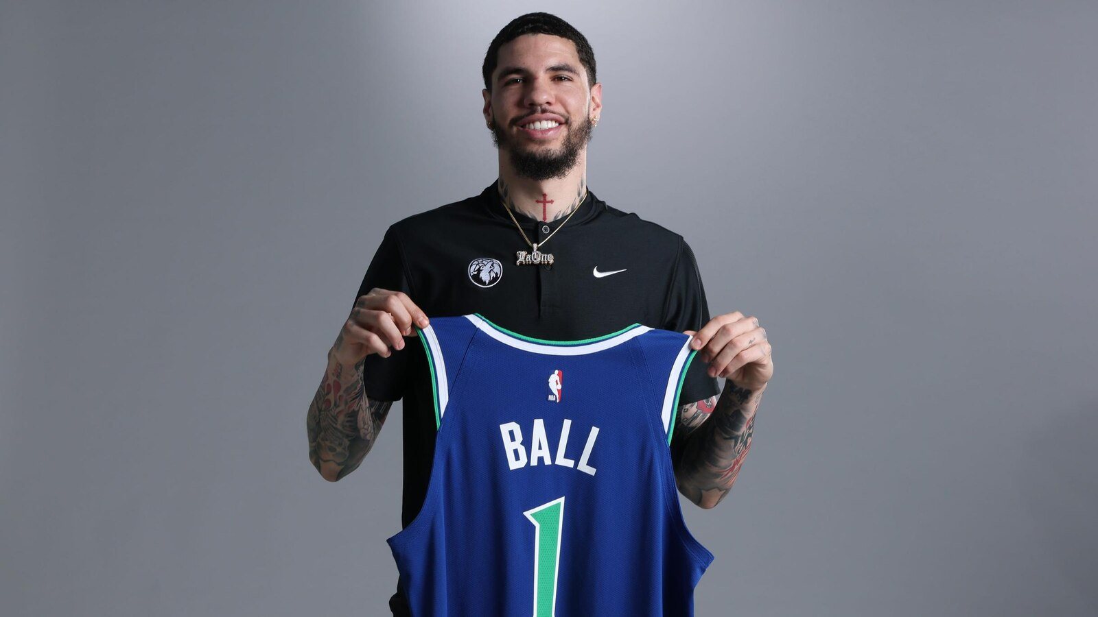 LaMelo Ball holds up a blue Timberwolves jersey bearing his name and number 1.