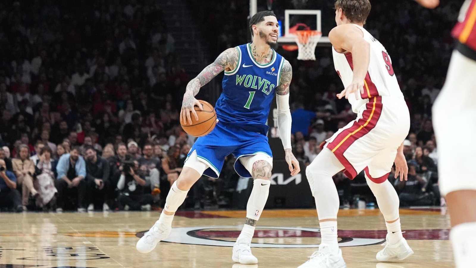LaMelo Ball dribbles in a blue Timberwolves uniform against a Miami Heat defender.