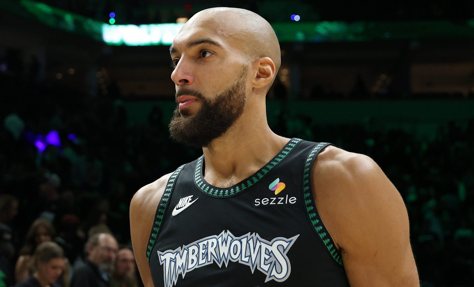 Rudy Gobert in a black Timberwolves jersey looks to his left during a game.