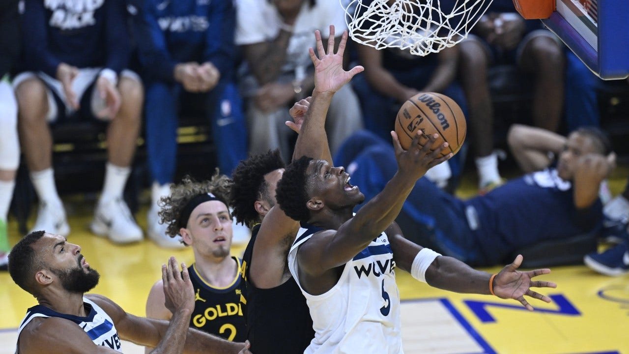 Anthony Edwards, in a white Wolves jersey, goes up for a layup against Golden State defenders as Rudy Gobert looks on.