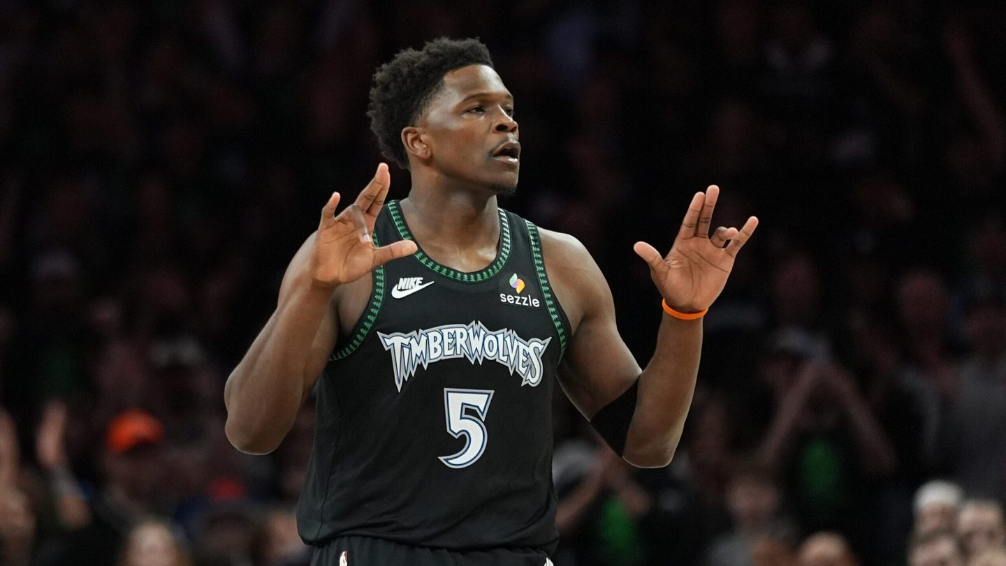Anthony Edwards holds up his hands in a black Timberwolves number 5 jersey.